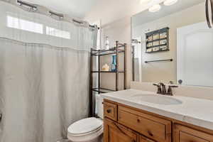 Bathroom featuring toilet, vanity, and curtained shower
