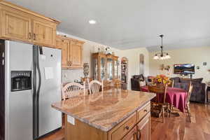 Kitchen featuring stainless steel fridge with ice dispenser, open floor plan, dark wood-style flooring, arched walkways, and recessed lighting