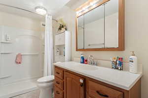Bathroom with vanity, a shower with curtain, toilet, and tile patterned flooring