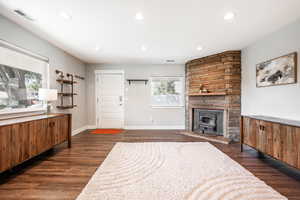 Living room with recessed lighting, dark wood-style floors, baseboards, and a wood stove