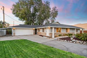Ranch-style home featuring stone siding, a garage, board and batten siding, driveway, and a front yard