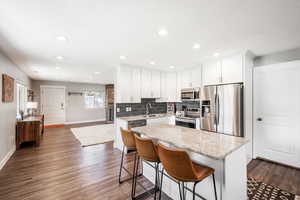 Kitchen with appliances with stainless steel finishes, a sink, baseboards, a kitchen island, and recessed lighting