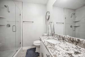 Bathroom with baseboards, toilet, vanity, and a shower stall