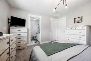 Carpeted bedroom with connected bathroom and baseboards