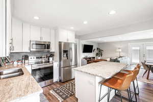 Kitchen featuring stainless steel appliances, a center island, dark wood-type flooring, white cabinetry, and open floor plan