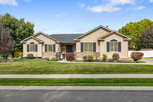 Single story home featuring stucco siding, a front yard, and stone siding