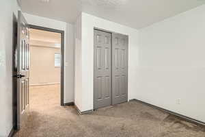 Unfurnished bedroom featuring carpet flooring, a closet, and baseboards