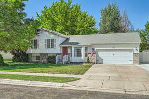 Split level home with a garage, a front lawn, driveway, and brick siding