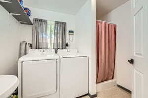 Washroom featuring independent washer and dryer, baseboards, and light tile patterned flooring