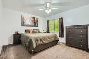 Bedroom with light colored carpet and a ceiling fan