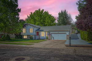 Split level home featuring a garage, driveway, and brick siding