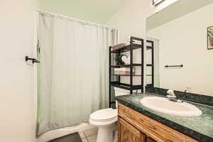 Bathroom featuring tile patterned flooring, vanity, toilet, and shower / bath combination with curtain