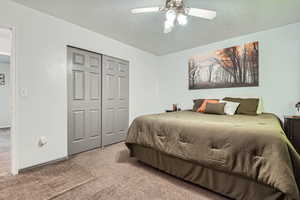 Carpeted bedroom featuring a closet, a textured ceiling, and ceiling fan