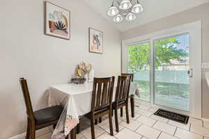 Dining room featuring a chandelier, lofted ceiling, light tile patterned floors, and baseboards