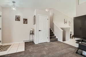 Carpeted entrance foyer with tile patterned flooring, stairway, and baseboards