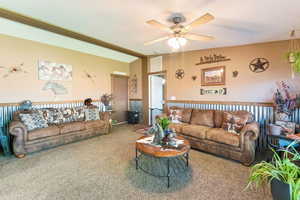 Living room featuring ceiling fan, carpet, and vaulted ceiling