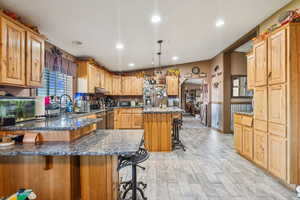 Kitchen featuring stainless steel appliances, a kitchen bar, a sink, dark stone countertops, and a peninsula