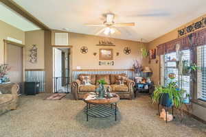 Living area with vaulted ceiling, carpet floors, and a ceiling fan
