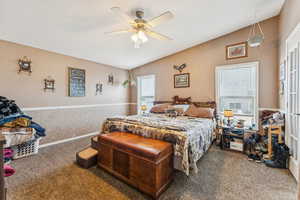 Carpeted bedroom featuring lofted ceiling and ceiling fan