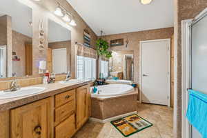 Full bath with a garden tub, double vanity, a shower stall, and stone finish flooring