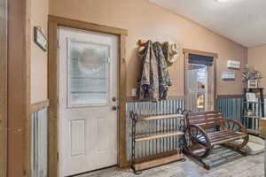 Entrance foyer with lofted ceiling, wood finished floors, and wainscoting