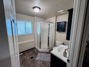 Bathroom featuring a shower stall, vanity, a textured ceiling, toilet, and tile patterned floors