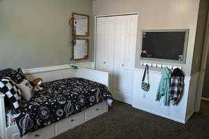 Bedroom featuring carpet flooring, a closet, and a wainscoted wall