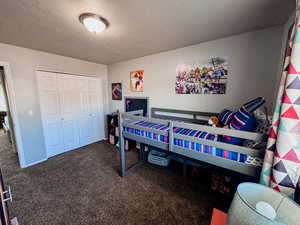 Bedroom with carpet floors, a textured ceiling, and a closet