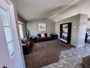 Living room with vaulted ceiling, baseboards, and carpet