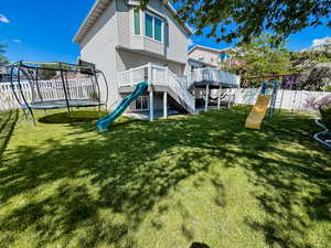 Back of house featuring a trampoline and a playground