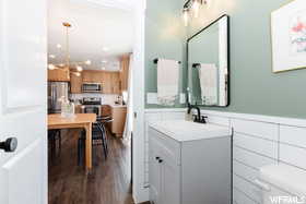 Bathroom featuring vanity, wood finished floors, a wainscoted wall, and toilet