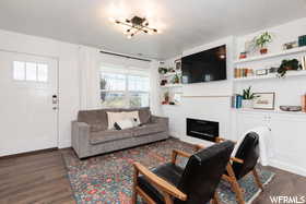 Living room featuring dark wood-style flooring, a chandelier, a glass covered fireplace, and built in shelves