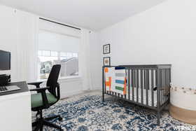Bedroom featuring a desk and a crib