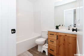 Full bath with vanity, toilet, wood finished floors, and  shower combination