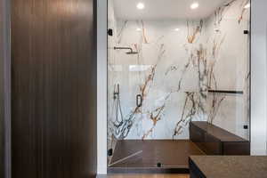 Full bath with a marble finish shower and recessed lighting
