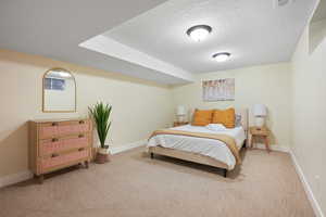Bedroom with light carpet, a textured ceiling, and baseboards