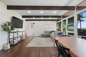 Living area with baseboards, wood finished floors, recessed lighting, and wooden ceiling with exposed beams