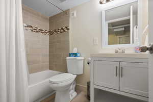 Full bath featuring toilet, a textured ceiling, shower / tub combo with curtain, vanity, and baseboards