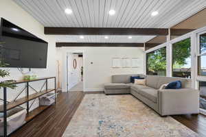 Living room featuring beamed ceiling, baseboards, dark wood-type flooring, and recessed lighting