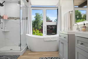 Bathroom featuring a marble finish shower, a freestanding bath, vanity, and wood finished floors