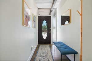 Doorway to outside featuring dark wood finished floors, baseboards, and beam ceiling