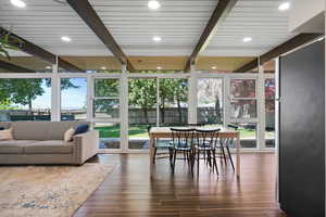 Sunroom / solarium with beamed ceiling, wood finished floors, and expansive windows