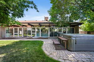 Rear view of house featuring a hot tub and a patio area