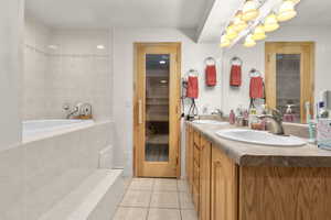 Full bathroom featuring tile patterned floors, double vanity, and tiled tub