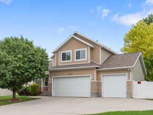 View of front of house with a garage, concrete driveway, stucco siding, roof with shingles, and brick siding