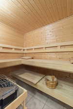 Sauna featuring tile patterned floors, wooden ceiling, and wooden walls