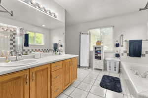 Full bath with double vanity, a bath, tile patterned floors, and a shower with shower door