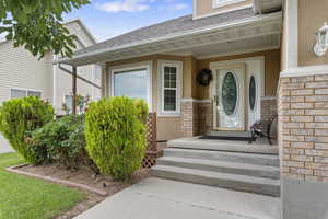 Doorway to property with stone siding, stucco siding, and a shingled roof