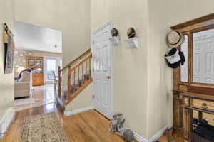 Entryway with light wood-style floors, baseboards, stairs, and a towering ceiling