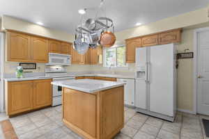 Kitchen featuring white appliances, a sink, light countertops, a center island, and recessed lighting
